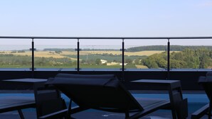 A poolside area with lounge chairs and a view of the countryside. - Kyriad Prestige - Sarrebourg Les Terrasses (Sarrebourg)