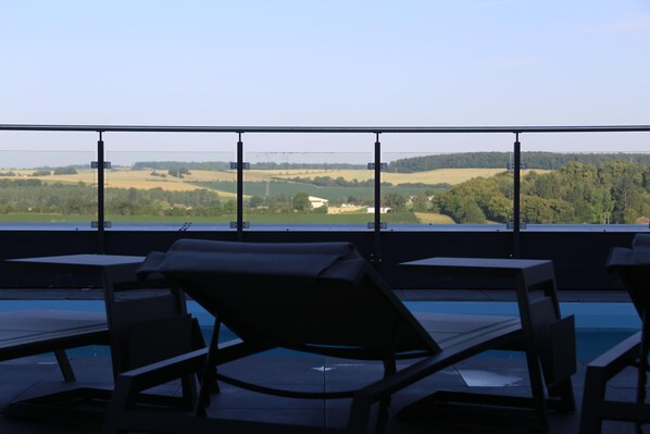 A poolside area with lounge chairs and a view of the countryside.