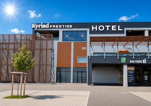 Una entrada moderna de hotel con un cartel que dice 'Kyriad Prestige Hotel' y el número 4 en la entrada.