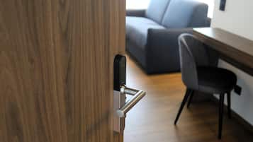 A wooden door with a modern handle, a grey office chair, and a grey sofa in the background.