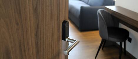 A wooden door with a modern handle, a grey office chair, and a grey sofa in the background.