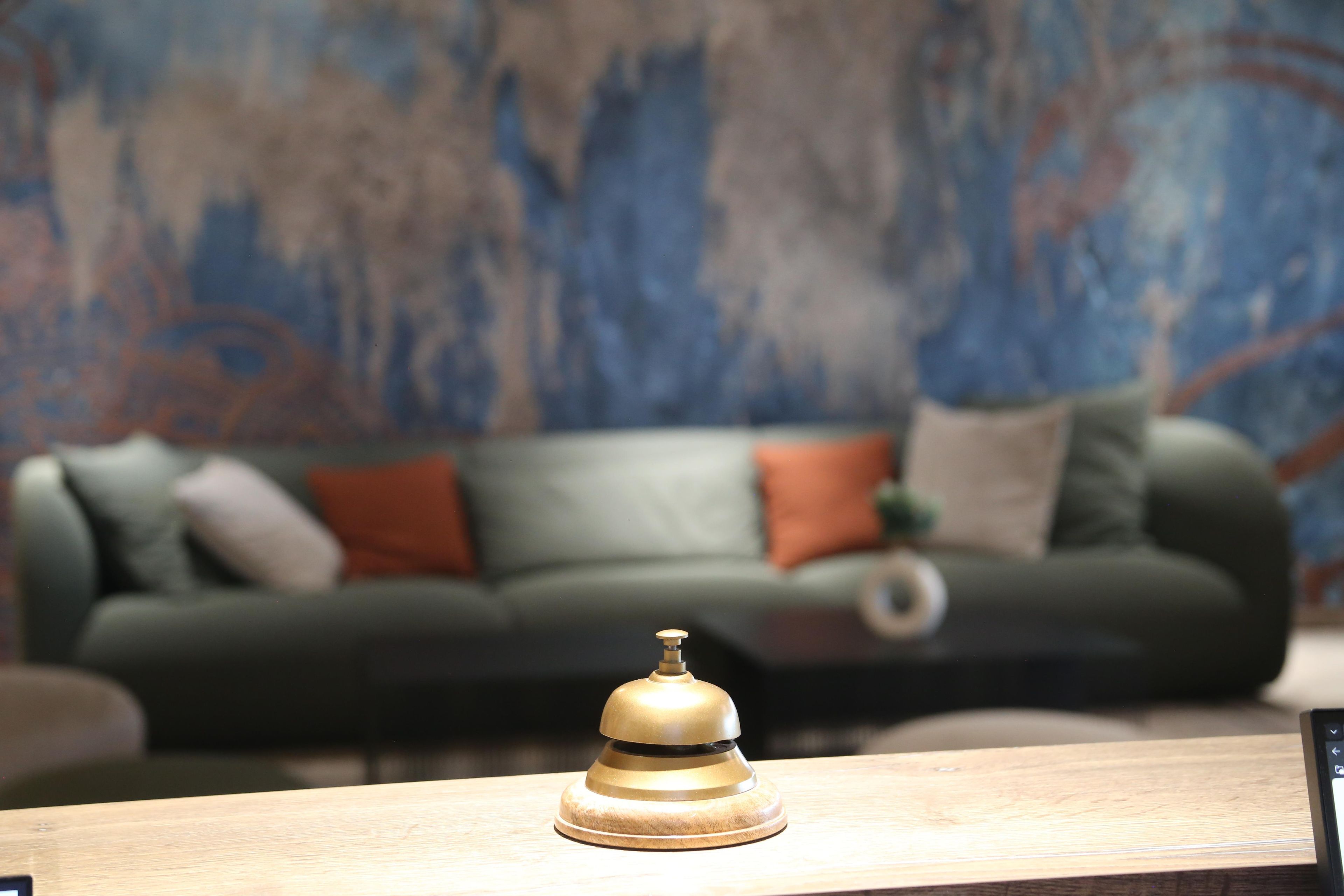Una habitación con una mesa de madera en primer plano y un sofá verde con cojines al fondo.