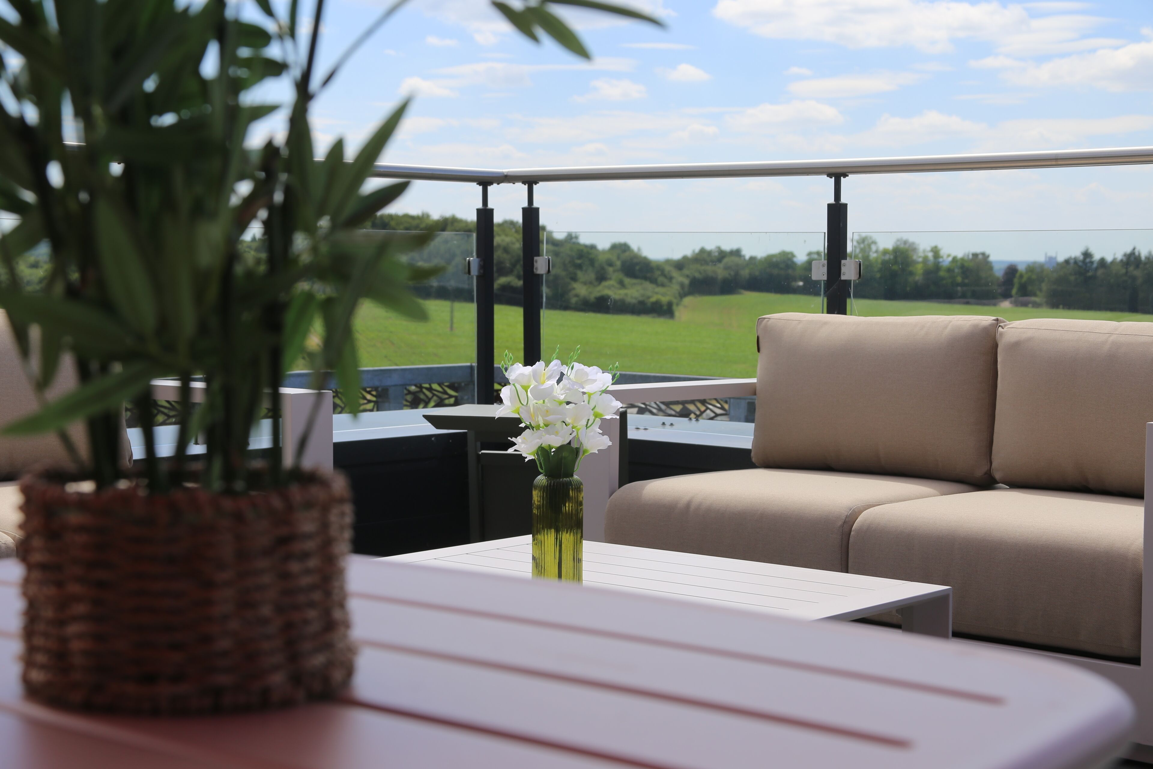 Un balcon avec un canapé, une table et un pot de fleurs.