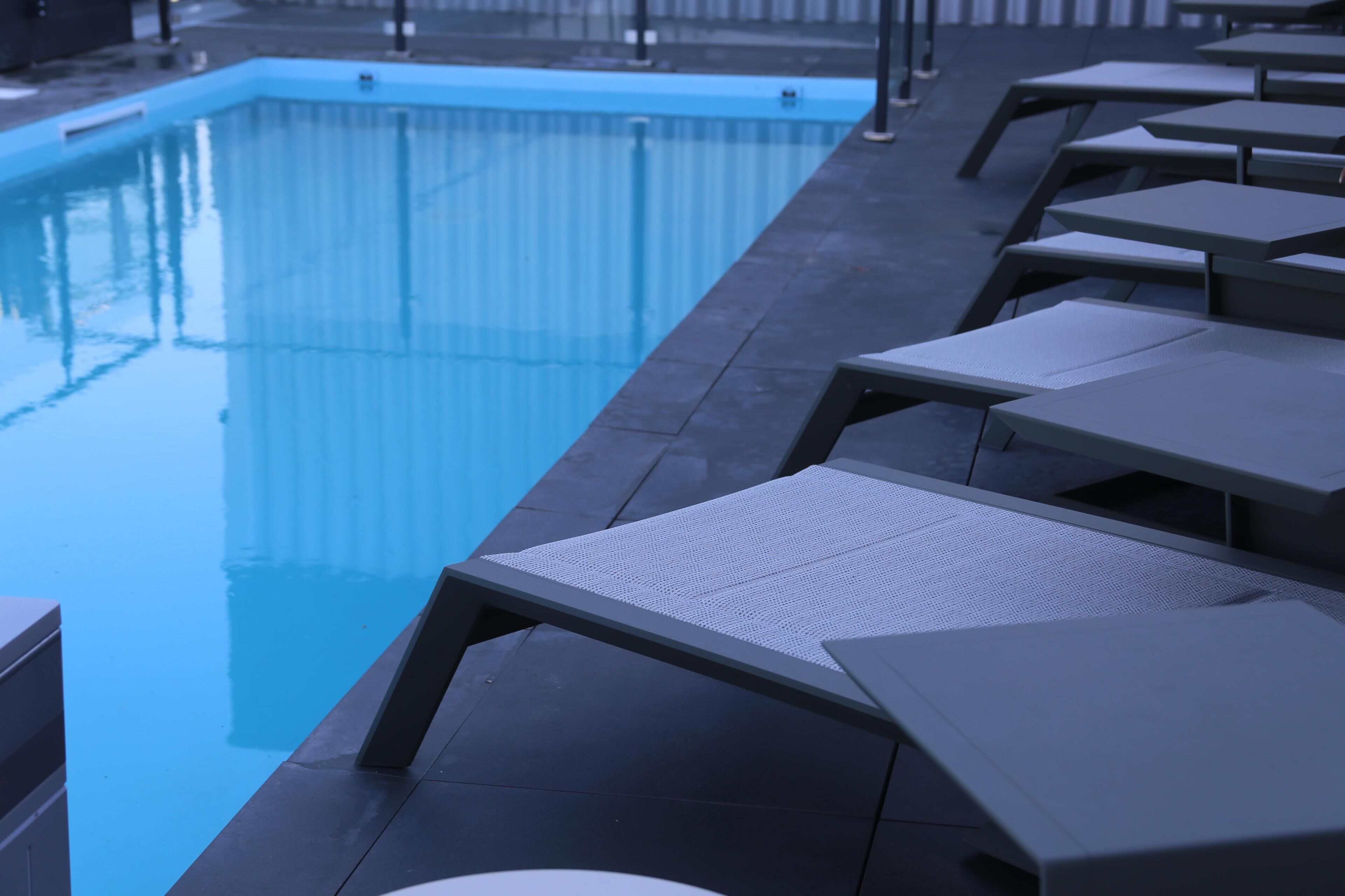 Une piscine avec des chaises longues et une terrasse carrelée.