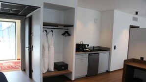 A compact hotel room with a kitchenette, a walk-in closet, and a view through an open door. - Kyriad Prestige - Sarrebourg Les Terrasses (Sarrebourg)