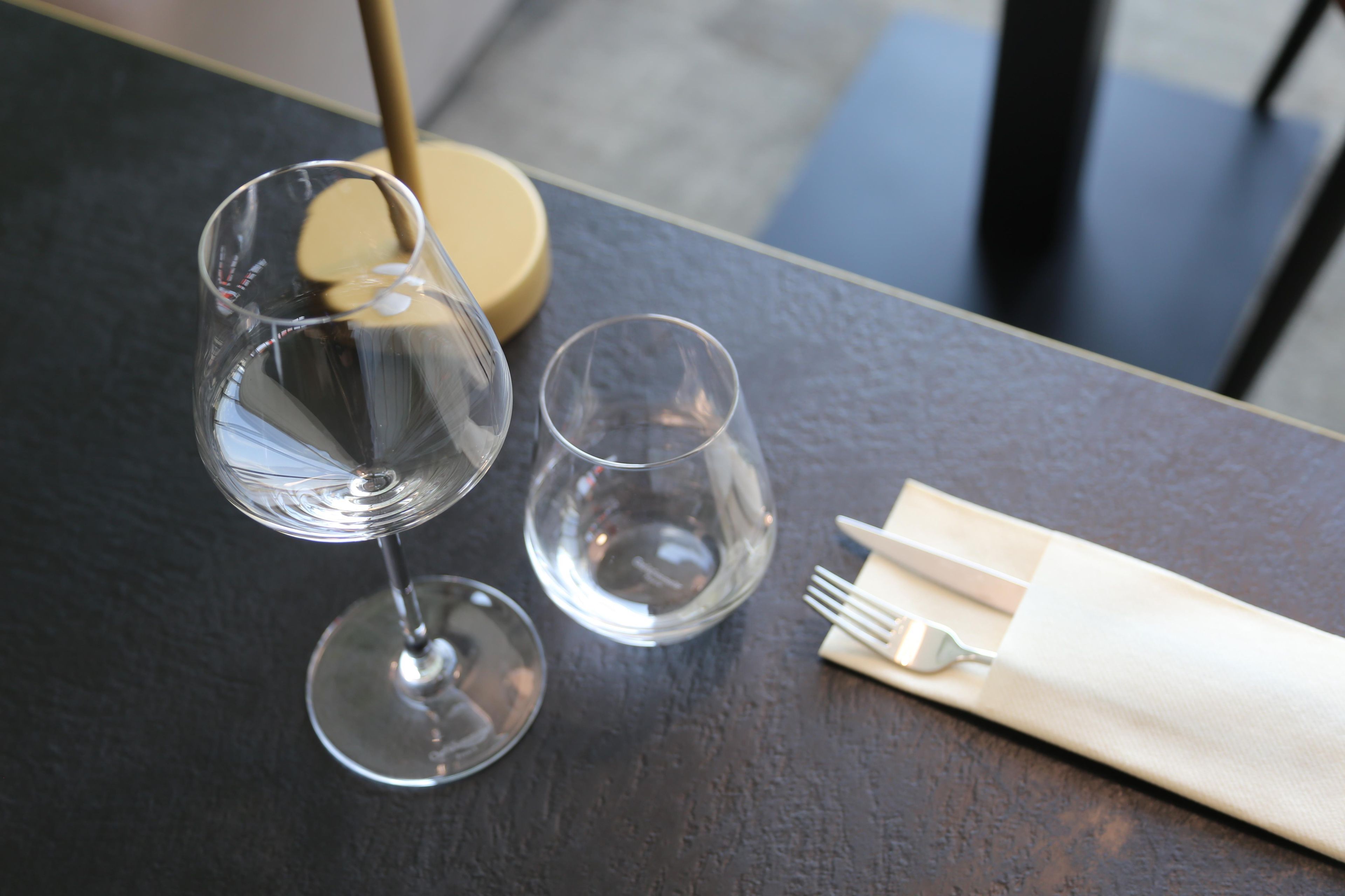 A table with two wine glasses and a folded napkin with a fork.