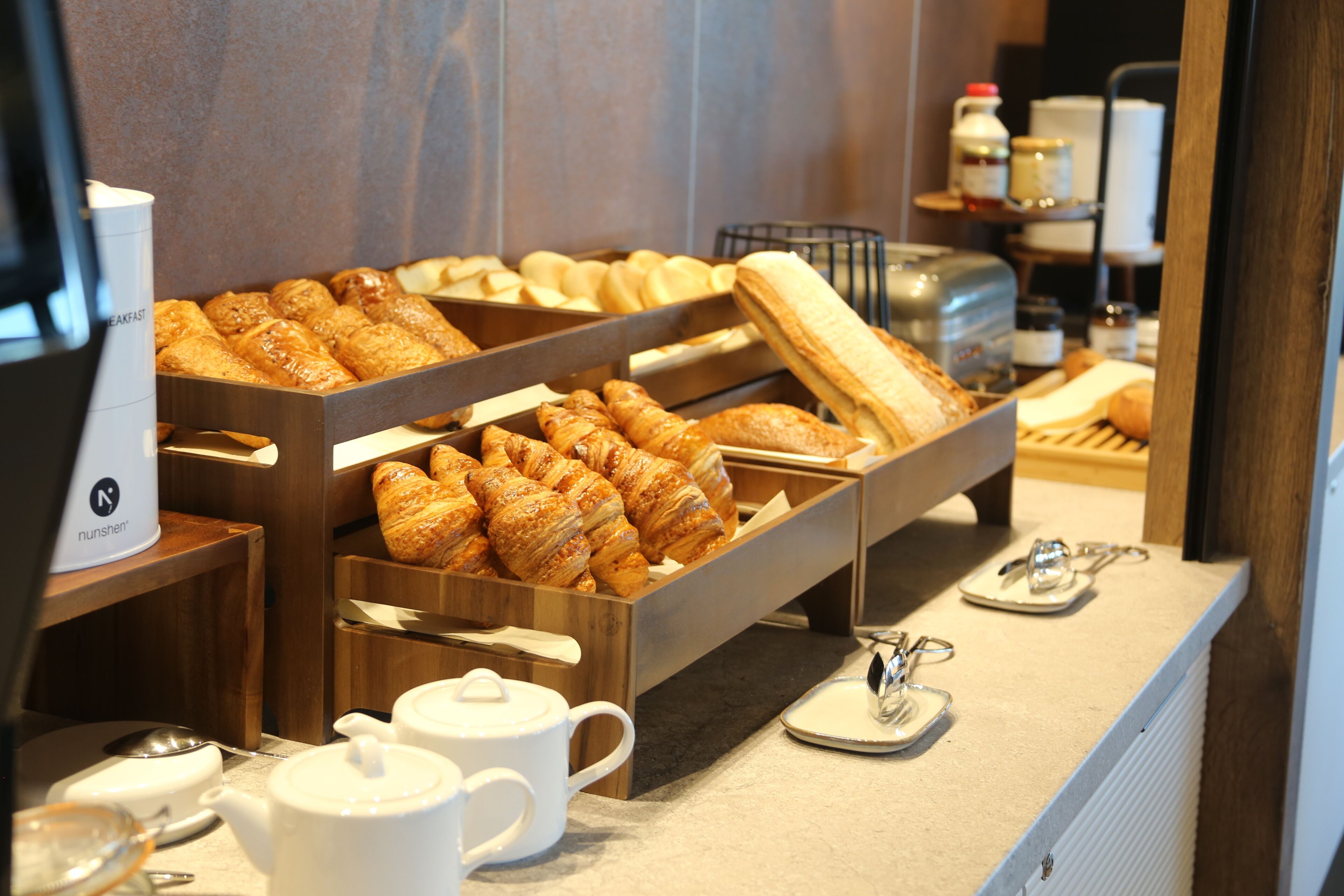A breakfast buffet with pastries, teapots, and a coffee machine.