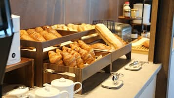 A breakfast buffet with pastries, teapots, and a coffee machine.