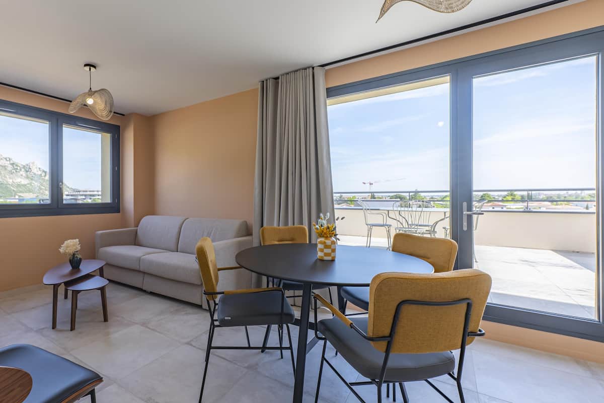 A modern living room with a sofa, dining table, chairs, and a TV.