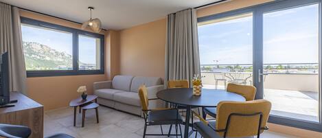 A modern living room with a sofa, dining table, chairs, and a TV.