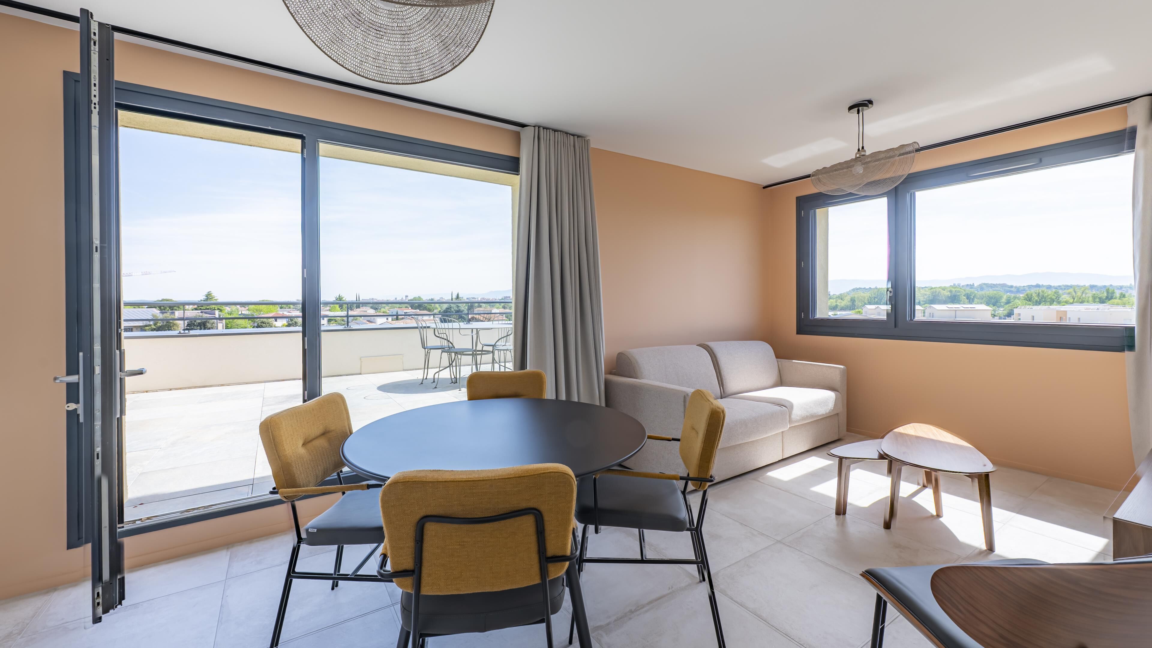 Ein modernes Zimmer mit Balkon, einem runden Tisch, Stühlen, einer Couch und einem kleinen Tisch.