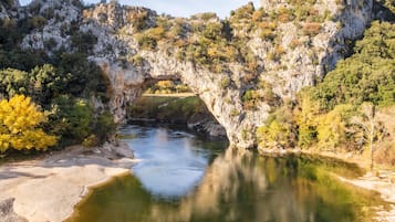 Un arco natural de roca sobre un río, con vegetación circundante.