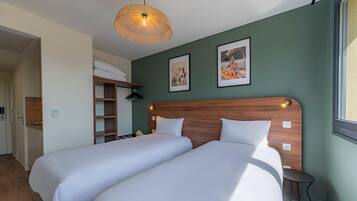 A room with two beds, a wooden headboard, a hanging light fixture, and a framed picture on the wall.