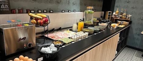 Un buffet per la colazione con diversi cibi e un cesto di frutta.