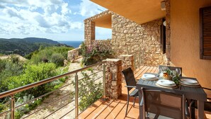 Un balcón con una pared de piedra, una mesa lista para comer y vistas del paisaje.
