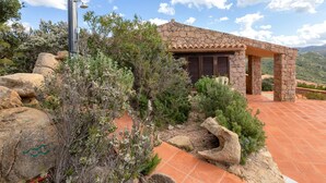 Una casa de piedra con un patio empedrado, rodeada de rocas y vegetación.