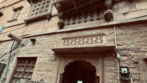 A building with a traditional architectural style, featuring ornate carvings and a wooden door. - HOTEL HIMMAT NIWAS (Jaisalmer)