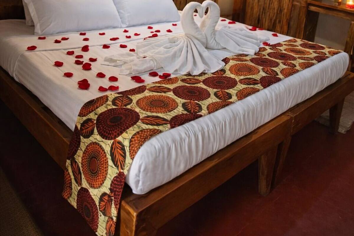 Un lit à baldaquin, avec du linge de lit blanc et une couverture décorative.