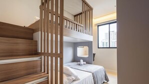Una camera da letto moderna con un letto a castello e un letto singolo, rivestimenti in legno sulle pareti, una finestra con vista sulla città e un comodino.