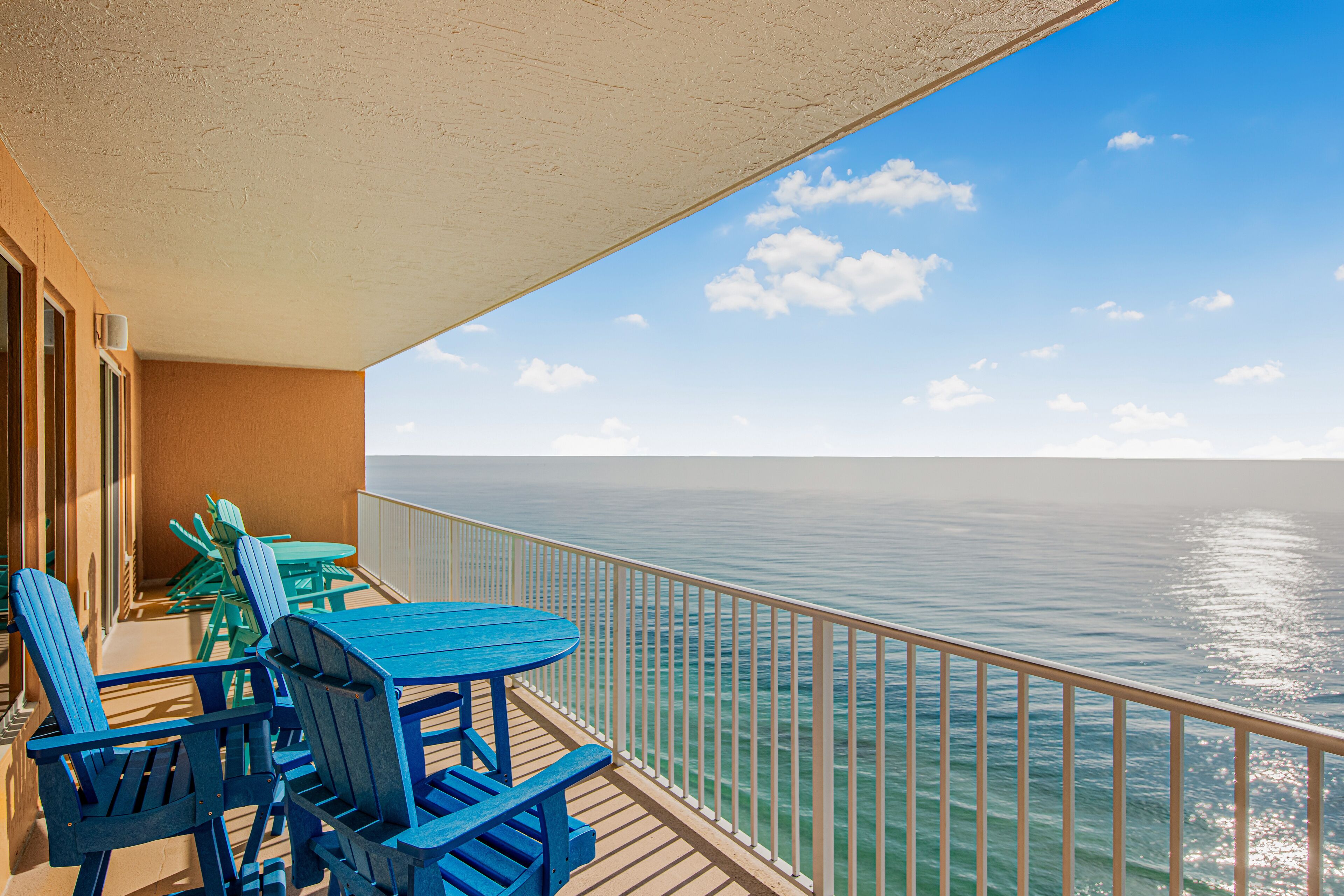 Un balcon avec une table et des chaises, donnant sur une mer calme.