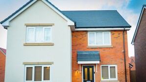 A two-story residential building with a beige facade, a black door, and a small front garden. - Luxury 4-Bedroom Family Home in Nuneaton Sleeps 10, Spacious, Safe & Comfortable (Nuneaton)