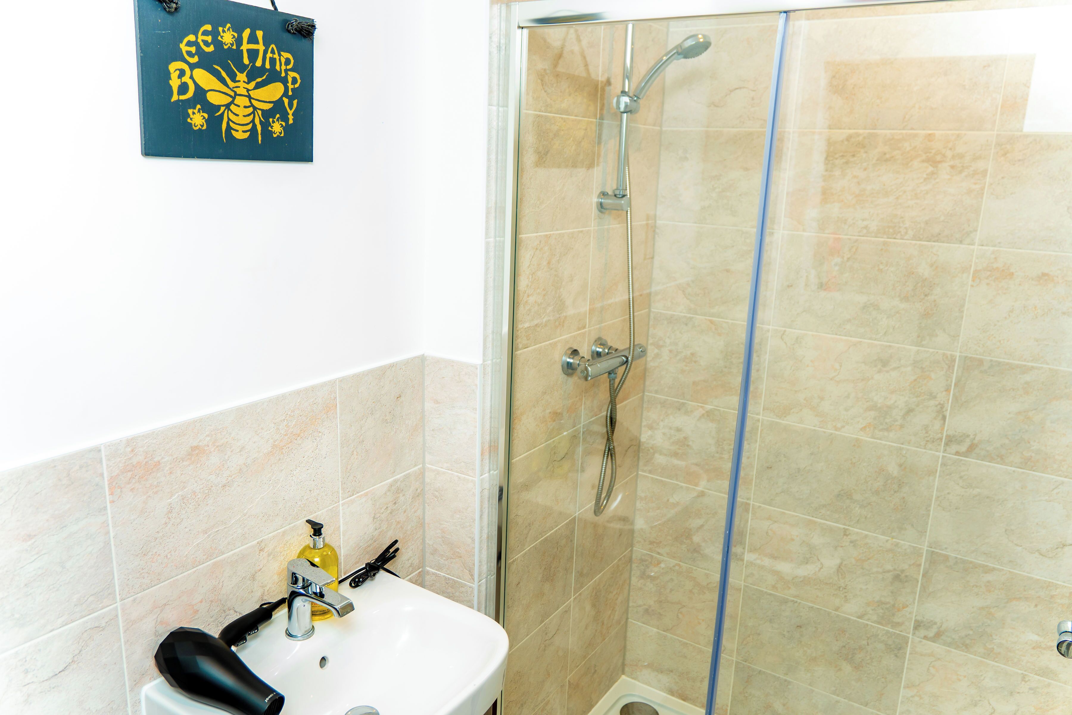 Une salle de bain équipée d’une douche, d’un lavabo et d’un panneau décoratif.