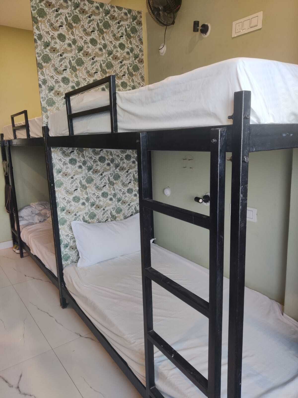 Camas literas con ropa de cama blanca, pared con estampado y suelo de baldosas.