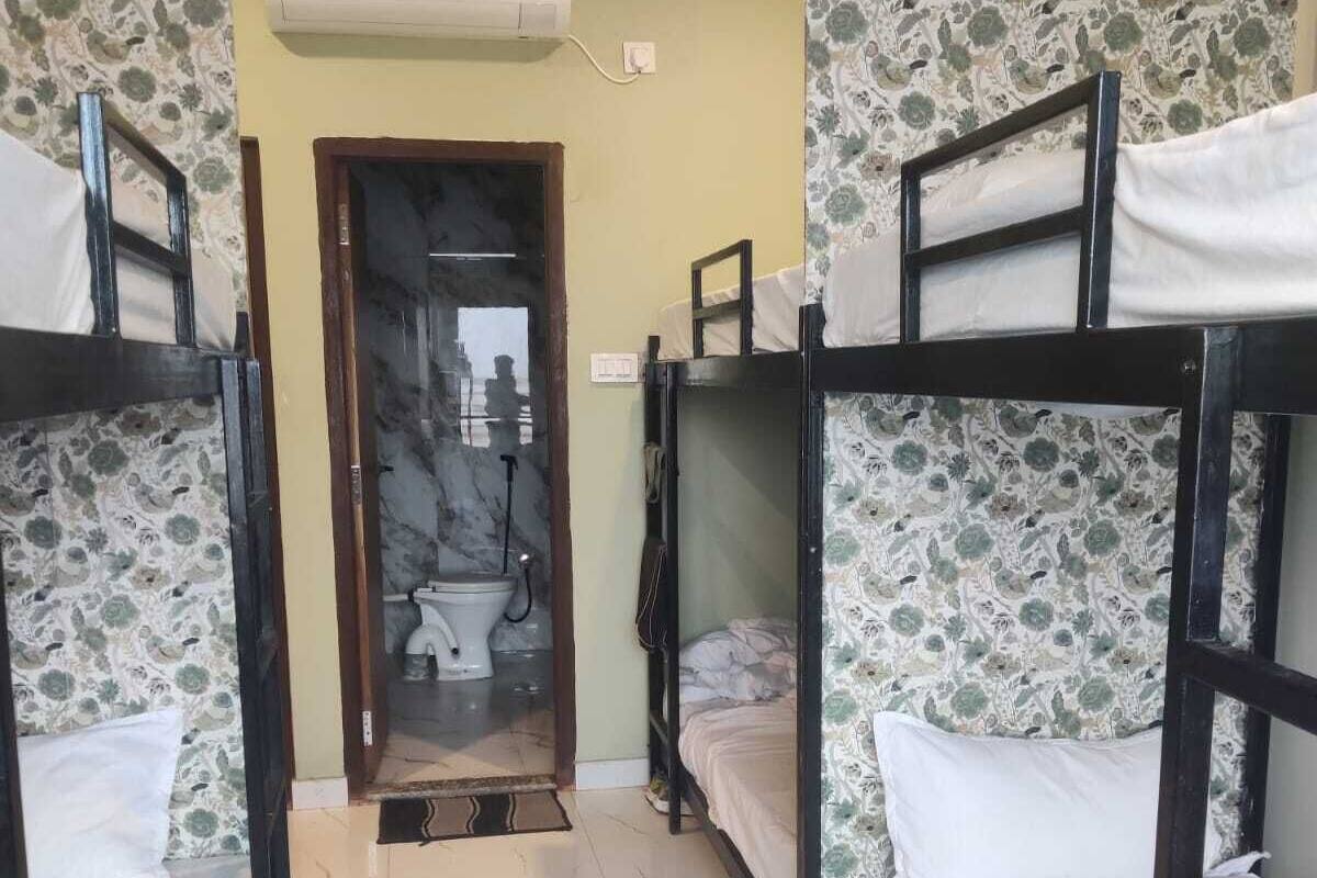 Una habitación con literas, baño con inodoro y lavamanos, y un equipo de aire acondicionado.