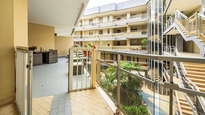 Un edificio residencial de varios niveles con balcones, un patio central con plantas y una escalera que conecta los pisos.