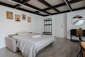 Een slaapkamer met een bed, nachtkastje, spiegel en kunstwerk aan de muur.