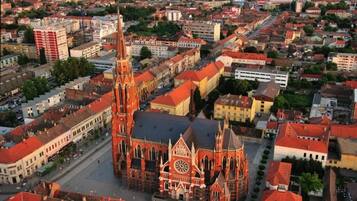 An aerial view of a city with a prominent red-brick church featuring a tall tower and a large circular window.