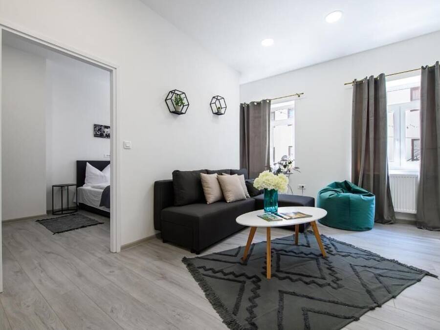 A modern living room with a dark sofa, a round coffee table, and a teal bean bag.
