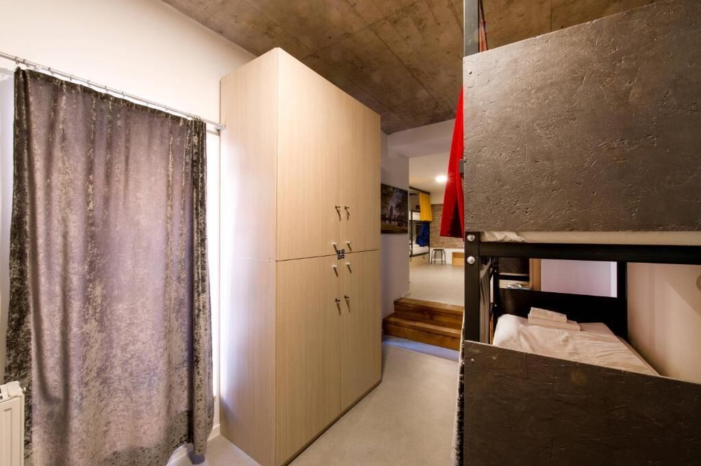 A compact room with a bunk bed, a wardrobe, and a curtain.