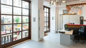 An office space with large windows, a desk with a computer, and a chair. - City Rooms OS (Osijek)