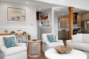 A modern living room with white furniture, a round coffee table, and a kitchen in the background. - ☀️ Pet Friendly - Steps to Beach - Private Pool and Hot Tub - The Lazy Turtle ☀️ (Cape San Blas)