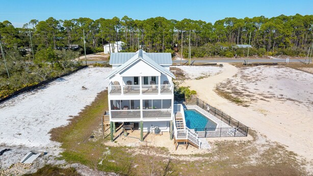 A two-story beachfront house with a pool, surrounded by sand and vegetation. - ☀️ Pet Friendly - Private Pool - Screened Deck - Indian Shores Cottage ☀️ (Indian Pass)