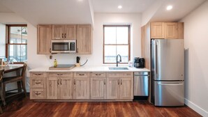 Eine moderne Küche mit Holzausstattung, einem Edelstahlkühlschrank und einer Mikrowelle.