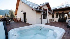 Ein Whirlpool auf einer Holzterrasse, im Hintergrund ein Haus.