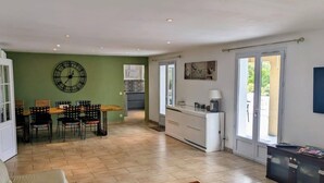 Un vaste espace de vie comprenant une table et des chaises en bois, un canapé et, au fond, une cuisine.