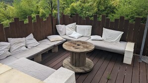 Un espace extérieur aménagé avec une terrasse en bois, une table ronde en bois et une clôture en bois.