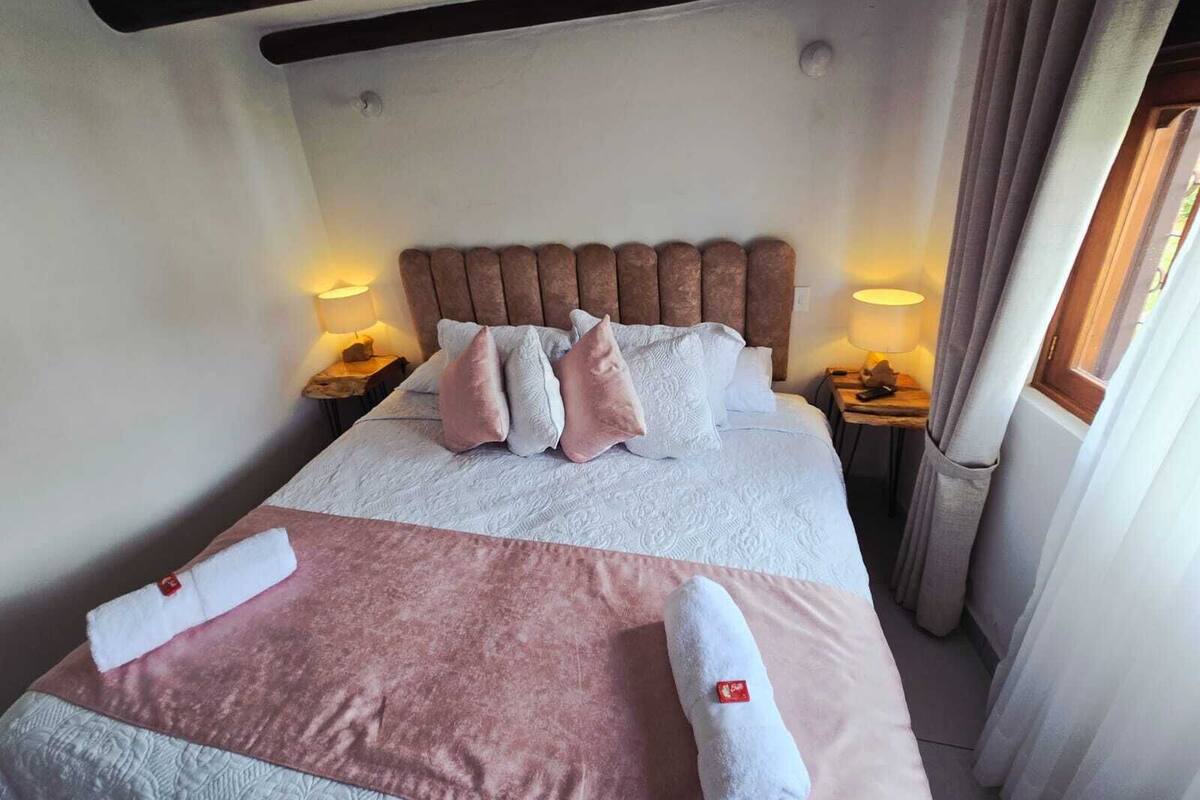 Un lit bien fait, avec des oreillers, une lampe de chevet et une serviette posée sur le lit.