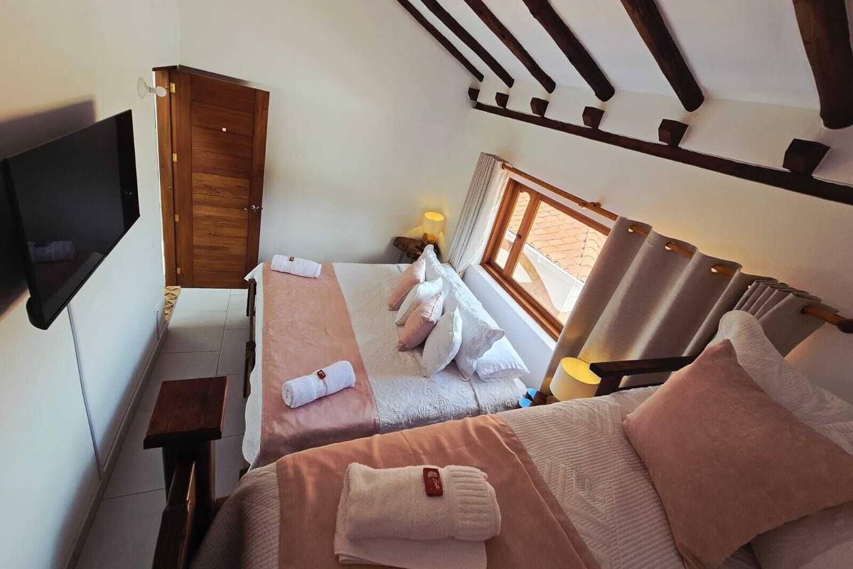 Une chambre avec deux lits, une télévision, une armoire en bois et une fenêtre avec des rideaux.