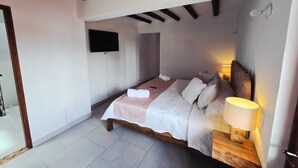 Ein Schlafzimmer mit Bett, Nachttischlampe und Fernseher an der Wand.