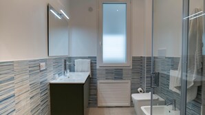 Ein modernes Badezimmer mit Duschkabine aus Glas, integriertem Waschbecken und Toilette.