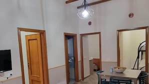 A living room with a sofa, a dining table with chairs, and a TV mounted on the wall. - La Pergola Apartment near Historic Ballarò Market (Palermo)