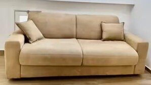 Un canapé beige dans un salon moderne, doté d’une lucarne et d’un mur sobre.
