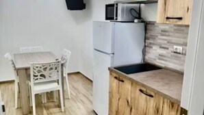 Une cuisine de taille réduite, avec un réfrigérateur blanc, un four à micro-ondes et des placards en bois.