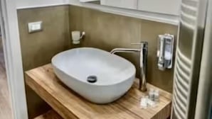 Um banheiro moderno com uma cuba grande, um móvel de vaidade em madeira e um espelho acima.
