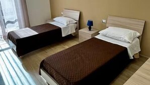 Ein Hotelzimmer mit zwei Betten, einem kleinen Tisch und einem Nachttisch mit Lampe.