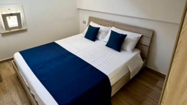 Une chambre à coucher avec un lit, un plancher en bois et une petite fenêtre.